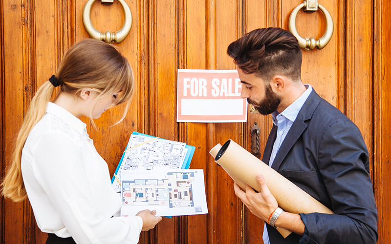 Real estate agents looking at floor plans in front of door