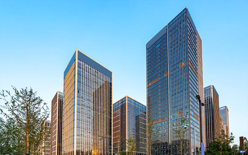 Modern glass skyscrapers stand tall against a clear blue sky.