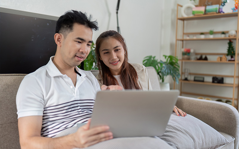 Couple researching Singapore property decoupling on a laptop.