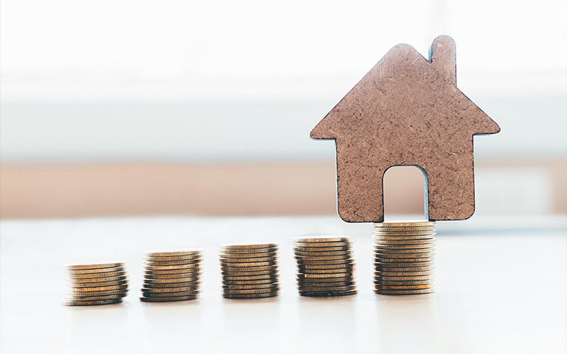 House model on stack of coins representing property value.